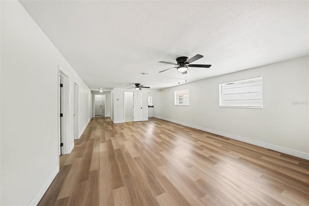An empty room with light wood-look flooring, white walls, two ceiling fans, and two windows — 2923 SANCHEZ STREET, TAMPA, FL