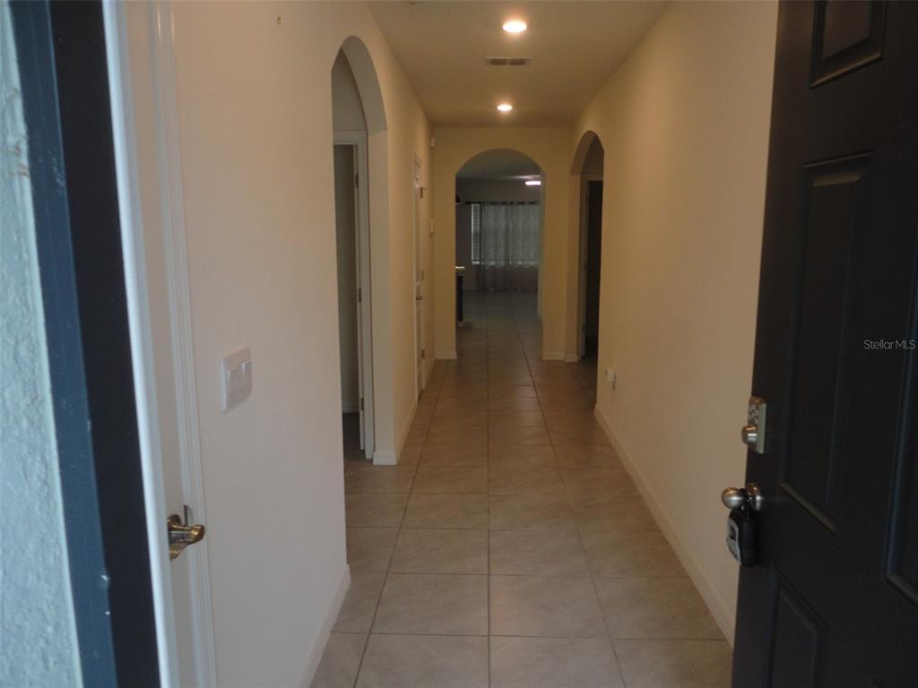 A tiled hallway with arched doorways leads from an open front door into the home — 216 HICKORY COURSE, OCALA, FL