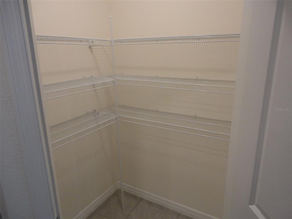 A walk-in pantry features white wire shelving installed on the walls — 216 HICKORY COURSE, OCALA, FL