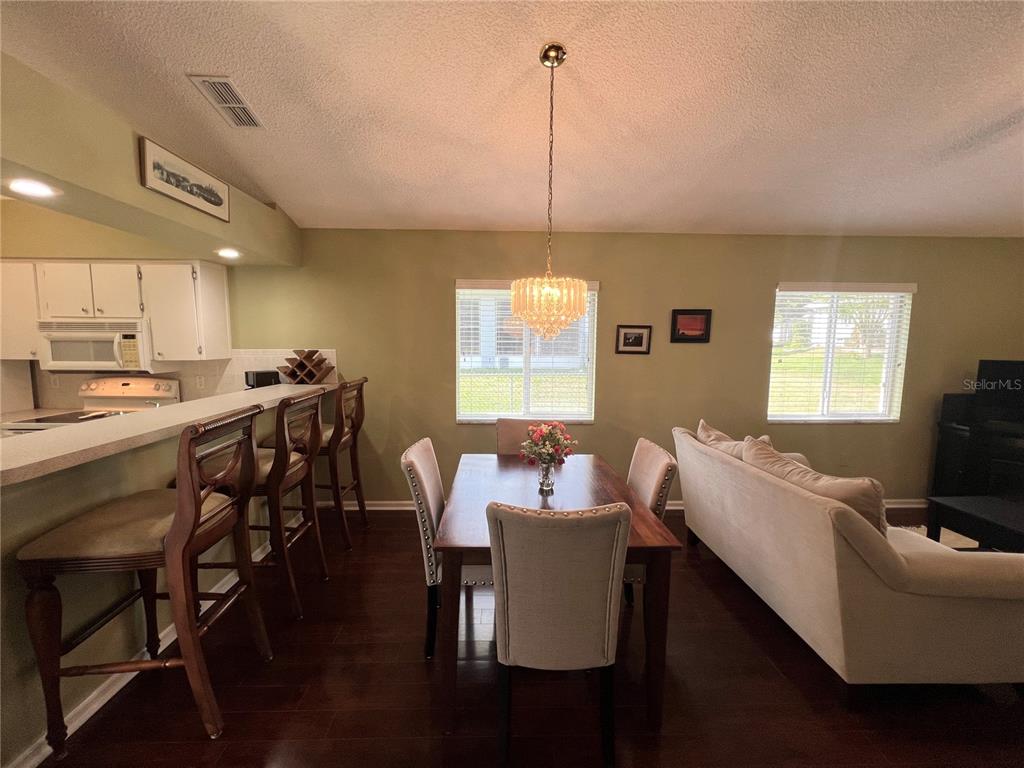 A dining area with a wooden table, upholstered chairs, and a breakfast bar with stools — 1918 NW 50TH CIRCLE, OCALA, FL