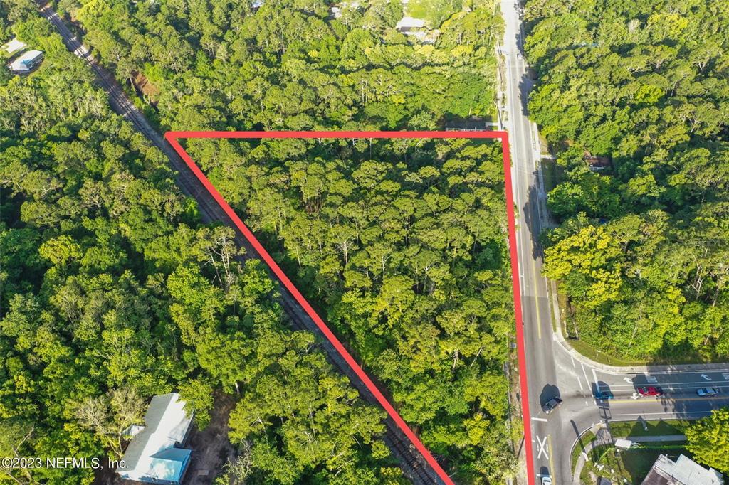 An aerial view shows a triangular, wooded lot bordered by a road and railroad tracks — 901 W KING STREET, ST AUGUSTINE, FL