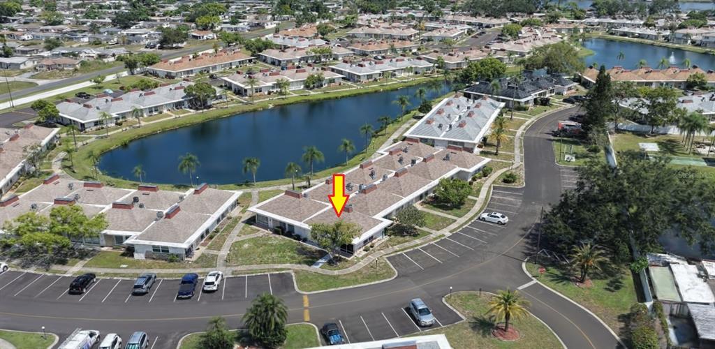 An aerial view shows a residential complex with multiple buildings, a pond, and parking lots — 4330 TAHITIAN GARDENS CIRCLE UNIT A, HOLIDAY, FL