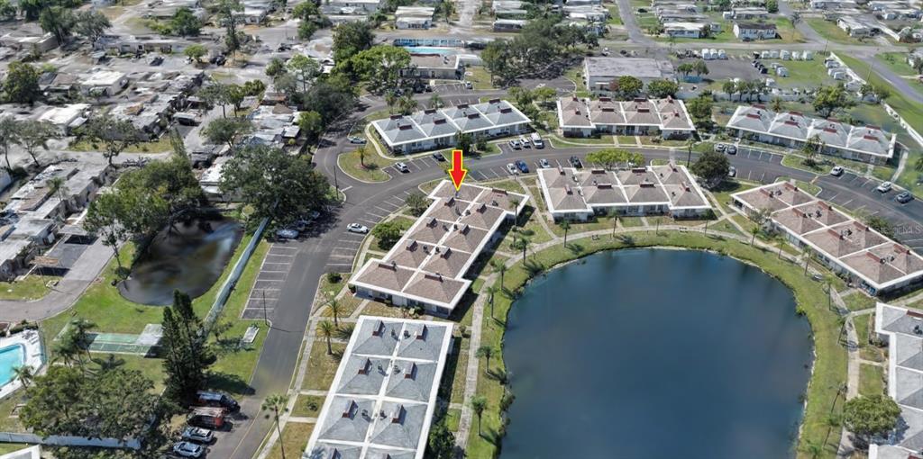 An aerial view shows a residential complex with multiple buildings surrounding a central pond — 4330 TAHITIAN GARDENS CIRCLE UNIT A, HOLIDAY, FL