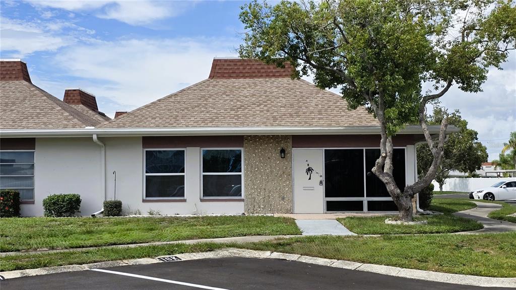 A single-story residential building with a brown shingled roof and a stone-accented exterior wall — 4330 TAHITIAN GARDENS CIRCLE UNIT A, HOLIDAY, FL
