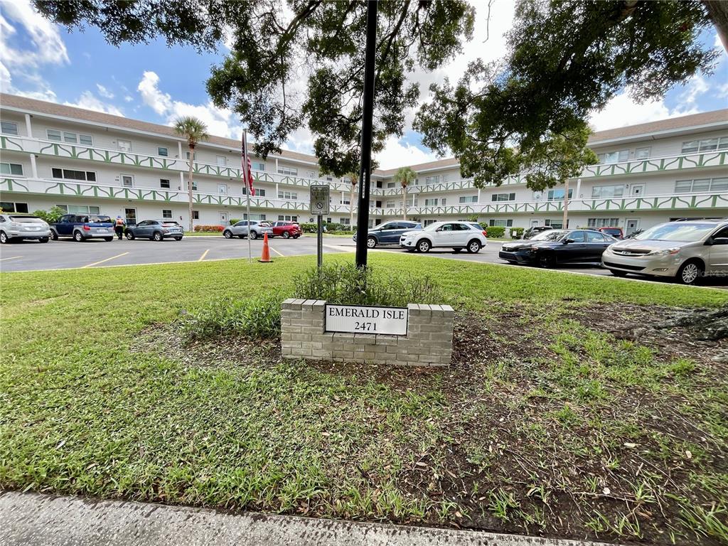 A brick sign for Emerald Isle stands in front of a multi-story apartment building — 2471 SUMATRAN WAY UNIT 43, CLEARWATER, FL