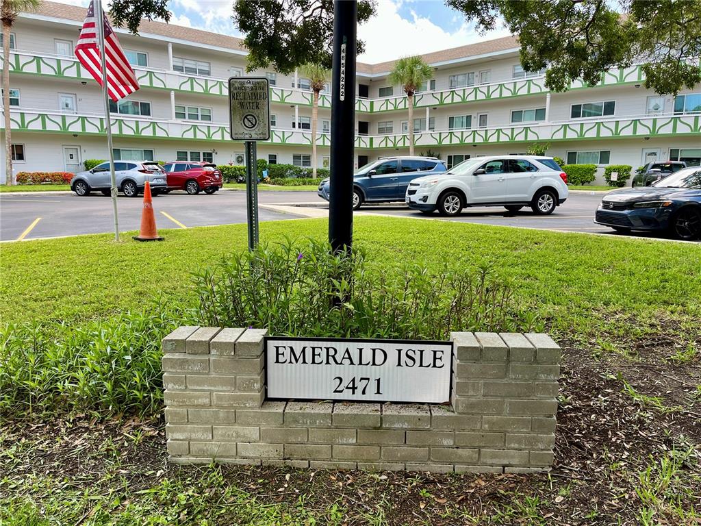 A brick sign for Emerald Isle stands in front of a multi-story apartment building — 2471 SUMATRAN WAY UNIT 43, CLEARWATER, FL