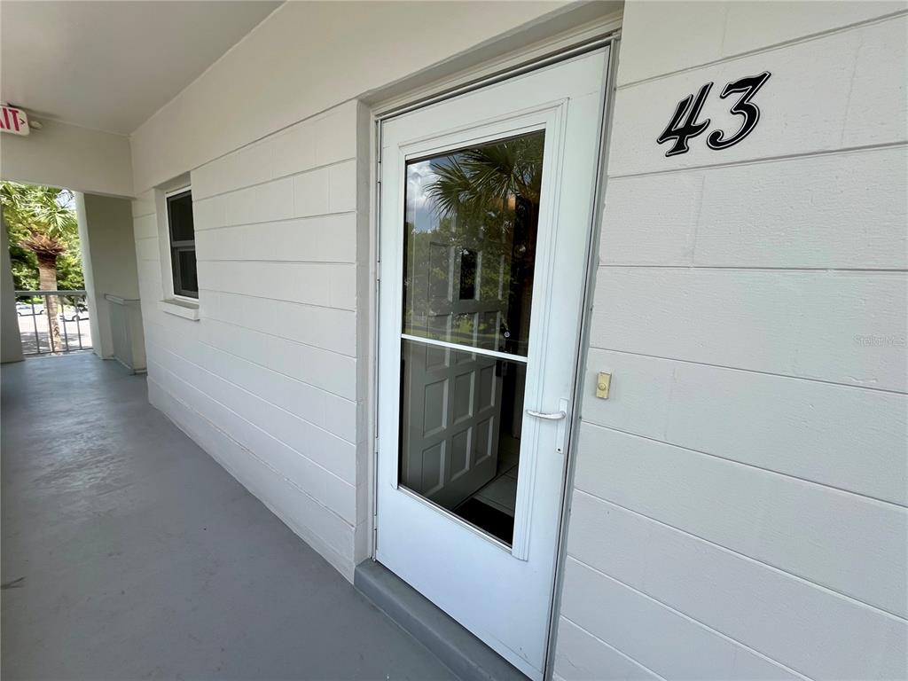 A white exterior door labeled 43 opens onto a covered concrete walkway — 2471 SUMATRAN WAY UNIT 43, CLEARWATER, FL