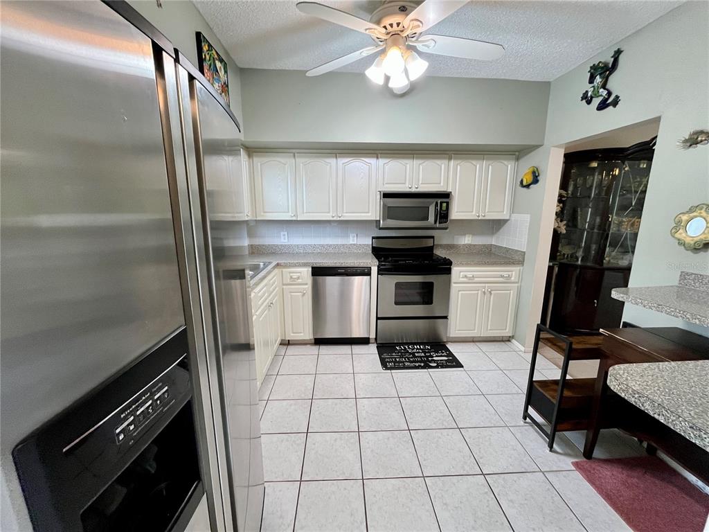 A kitchen with white cabinets, stainless steel appliances, and light-colored tile flooring — 2471 SUMATRAN WAY UNIT 43, CLEARWATER, FL