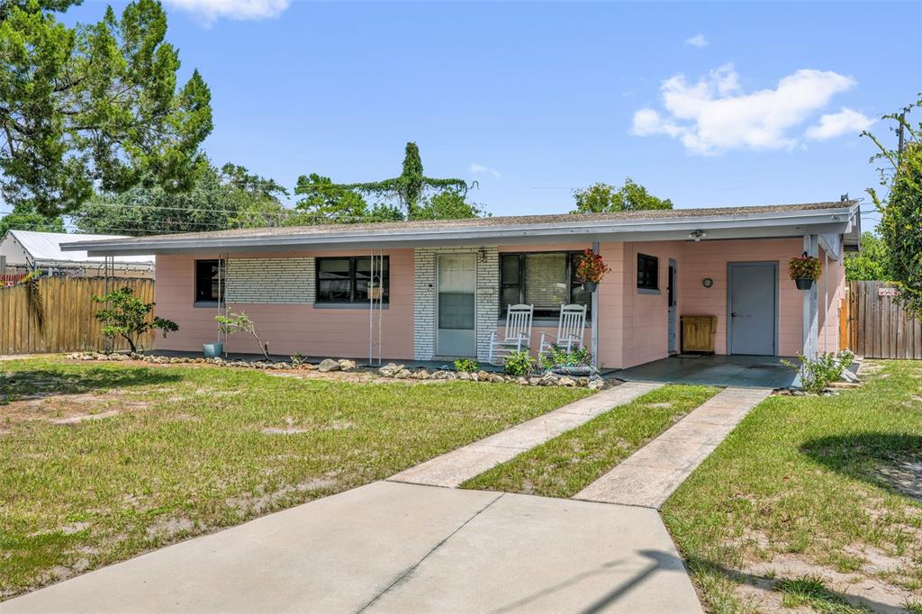 A single-story pink house with a flat roof, white brick accents, and a concrete driveway — 6409 RAMIR ROAD, ORLANDO, FL
