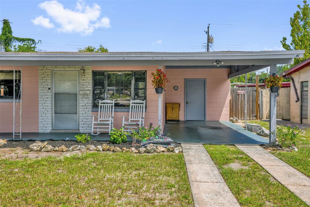 A pink single-story house features a front porch, a carport, and two white rocking chairs — 6409 RAMIR ROAD, ORLANDO, FL