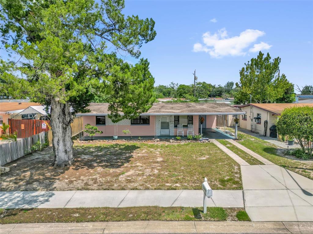 A single-story pink house with a carport, a large tree, and a concrete driveway — 6409 RAMIR ROAD, ORLANDO, FL