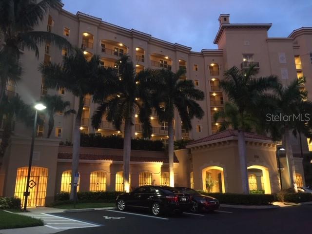 A multi-story residential building with palm trees and a parking area in front at dusk — 3321 SUNSET KEY CIRCLE UNIT 308, PUNTA GORDA, FL