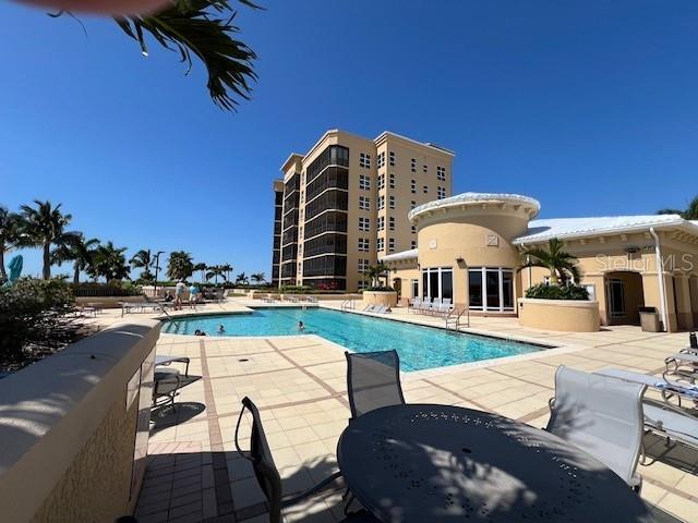 A swimming pool sits on a patio in front of a multi-story residential building — 3321 SUNSET KEY CIRCLE UNIT 308, PUNTA GORDA, FL