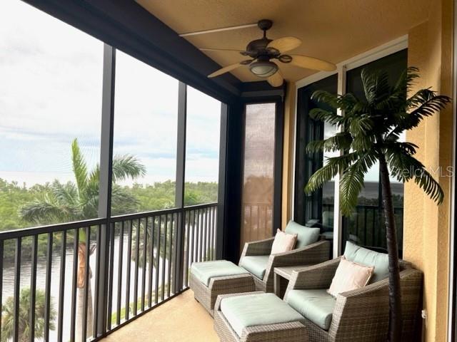 A screened-in balcony features wicker chairs, ottomans, a ceiling fan, and a view of water — 3321 SUNSET KEY CIRCLE UNIT 308, PUNTA GORDA, FL