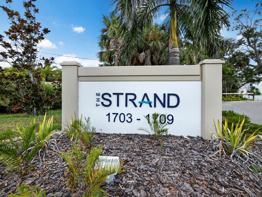 A sign for The Strand stands in a landscaped area with palm trees and mulch — 1709 N TAMIAMI TRAIL UNIT 418, SARASOTA, FL