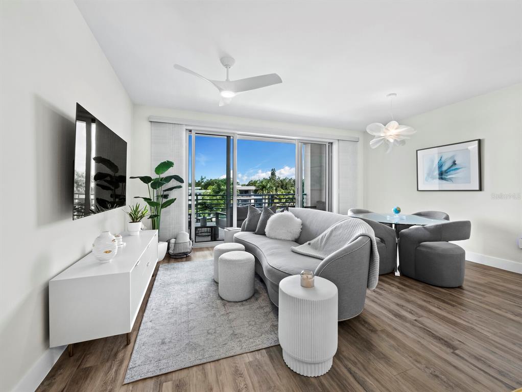 A modern living and dining room features a grey curved sofa, white furniture, and balcony — 1709 N TAMIAMI TRAIL UNIT 418, SARASOTA, FL