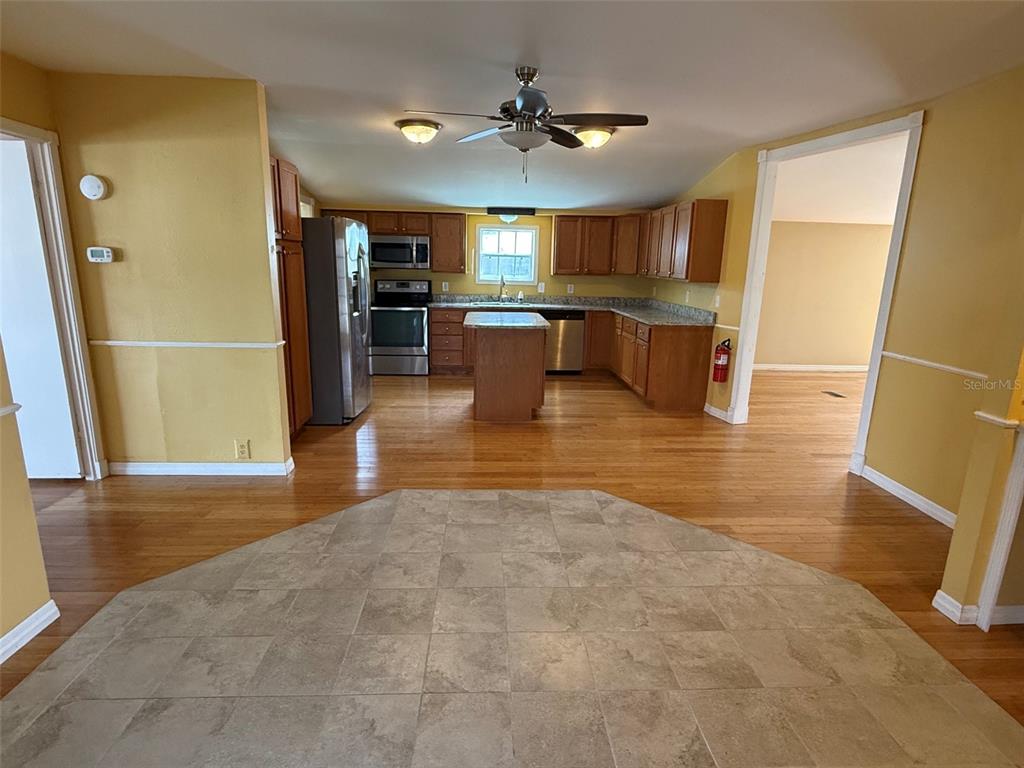 A kitchen features wood cabinets, stainless steel appliances, a center island, and hardwood flooring — 3022 SHORT LEAF STREET, WESLEY CHAPEL, FL