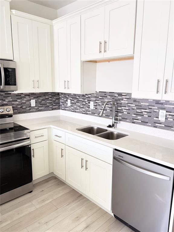 A kitchen features white cabinets, stainless steel appliances, a double sink, and a mosaic backsplash — 1619 CUMIN DRIVE, POINCIANA, FL
