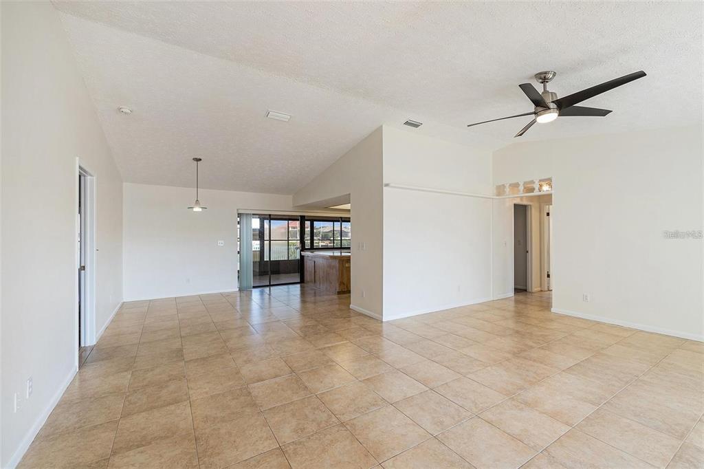 A spacious, open-concept living area features light-colored tile flooring, white walls, and a ceiling fan — 909 CHIPAWAY DRIVE, APOLLO BEACH, FL