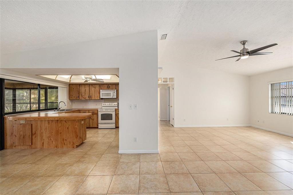 An open-concept living area features tile flooring, a kitchen with wood cabinets, and vaulted ceilings — 909 CHIPAWAY DRIVE, APOLLO BEACH, FL