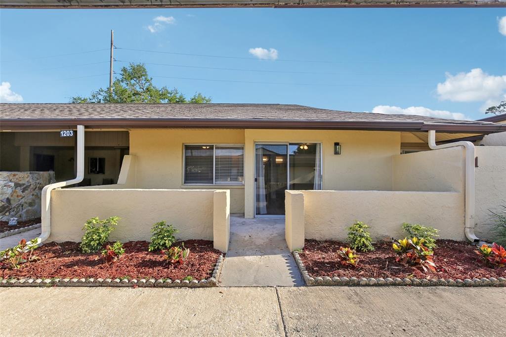 A single-story yellow stucco building with a small front patio and low perimeter wall — 1203 16TH CIRCLE SE, LARGO, FL