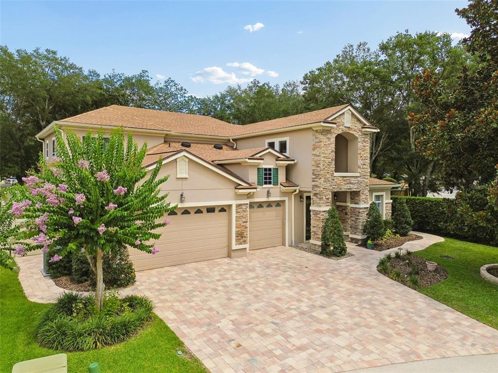 A two-story house with a stone facade, tan stucco, and a paved driveway — 1489 ARBITUS CIRCLE, OVIEDO, FL