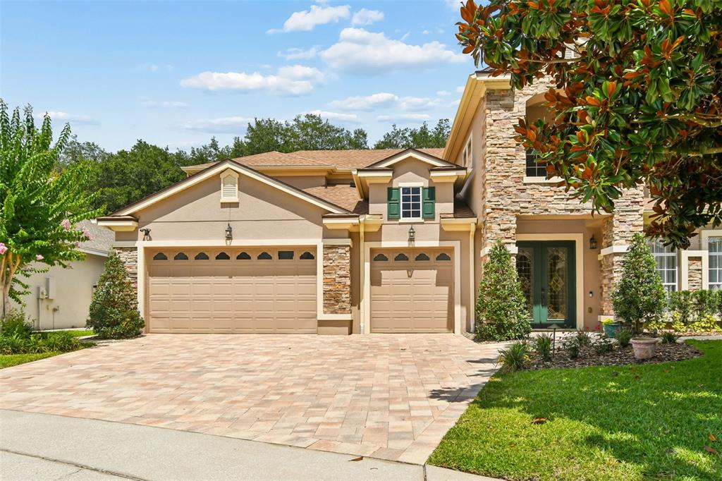 A two-story house with a three-car garage, stone accents, and a paved driveway — 1489 ARBITUS CIRCLE, OVIEDO, FL