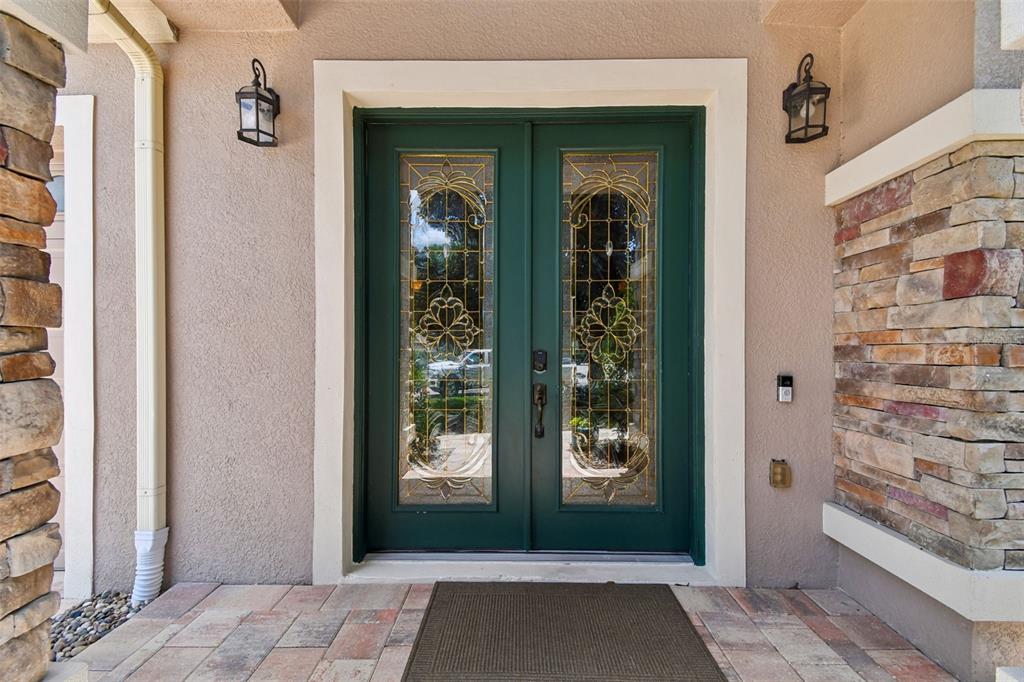 A dark green double front door with decorative glass panels sits between stone-accented exterior walls — 1489 ARBITUS CIRCLE, OVIEDO, FL
