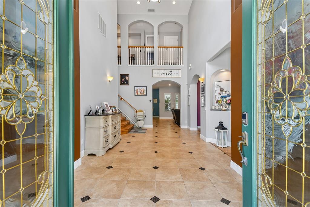 A tiled foyer features a high ceiling, a staircase, and a view into the home — 1489 ARBITUS CIRCLE, OVIEDO, FL