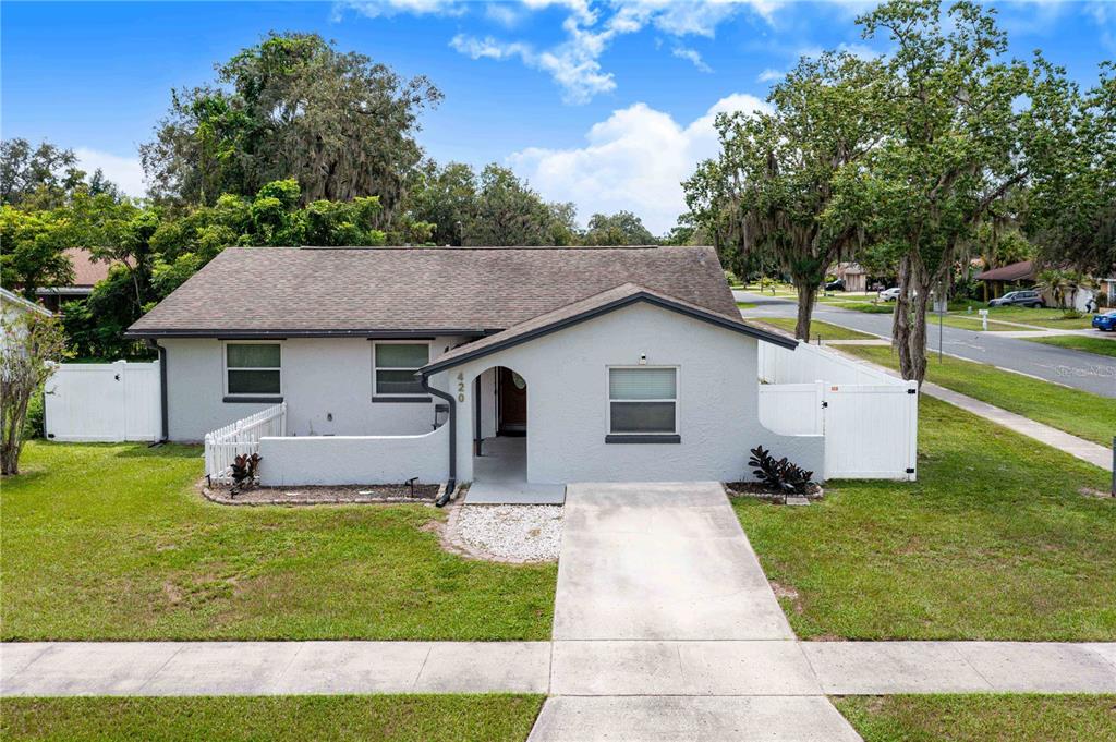 A single-story gray house with a concrete walkway and white privacy fencing in the yard — 420 NANTAHALA COURT, CASSELBERRY, FL