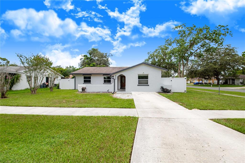 A single-story gray house with a concrete driveway and lawn under a blue sky — 420 NANTAHALA COURT, CASSELBERRY, FL