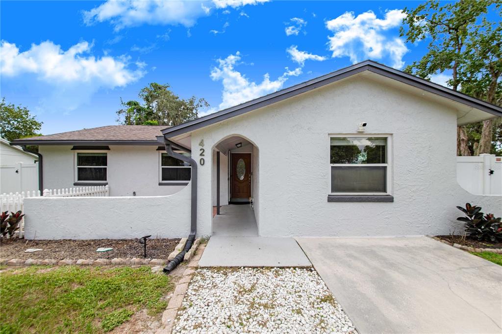 A single-story house with white stucco walls, a dark roof, and a recessed front entrance — 420 NANTAHALA COURT, CASSELBERRY, FL