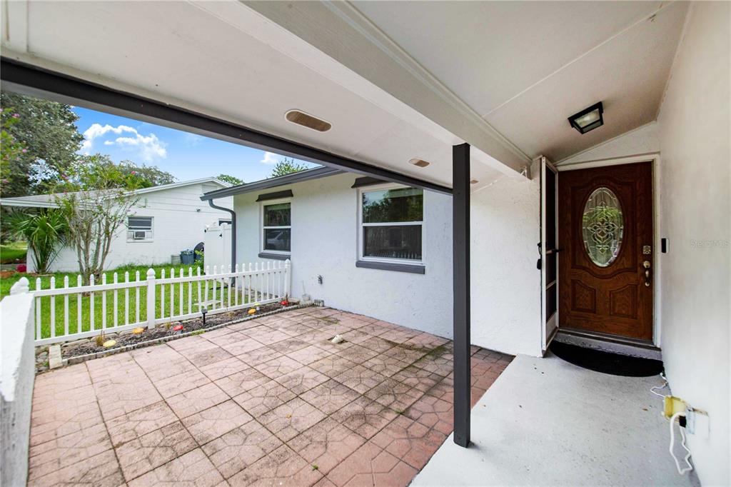 A covered patio with a tiled floor and white fence leads to a wooden front door — 420 NANTAHALA COURT, CASSELBERRY, FL