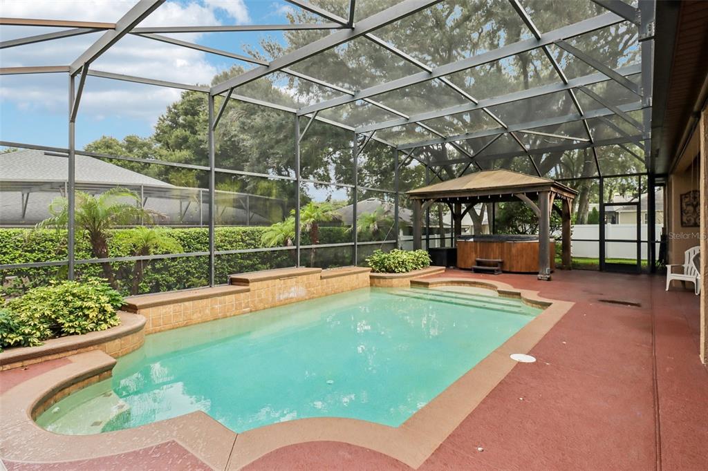 A screened-in pool area features a built-in spa, a gazebo, and a red concrete deck — 2947 CEDAR CREST DRIVE, APOPKA, FL