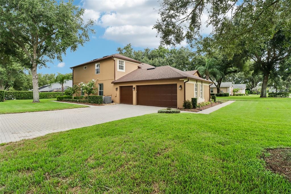 A two-story tan house with a three-car garage and a paved driveway on a lawn — 2947 CEDAR CREST DRIVE, APOPKA, FL