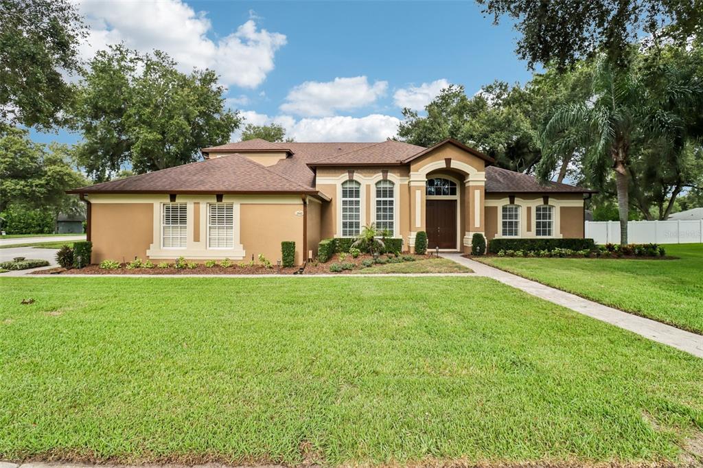 A single-story tan house with a brown roof, arched entryway, and a large front lawn — 2947 CEDAR CREST DRIVE, APOPKA, FL