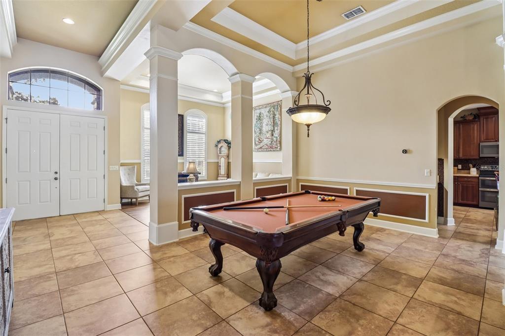 A pool table sits in a tiled room with arched columns and a tray ceiling — 2947 CEDAR CREST DRIVE, APOPKA, FL