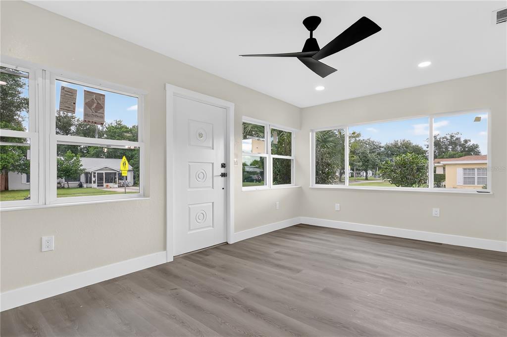 A bright living room features light gray wood-look flooring, a white door, and large windows — 2612 ROXBURY ROAD, WINTER PARK, FL