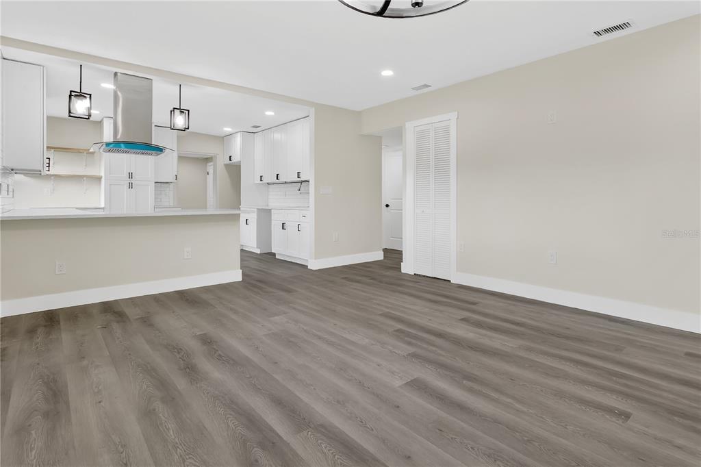 A view of a kitchen with white cabinets and a living area with gray flooring — 2612 ROXBURY ROAD, WINTER PARK, FL