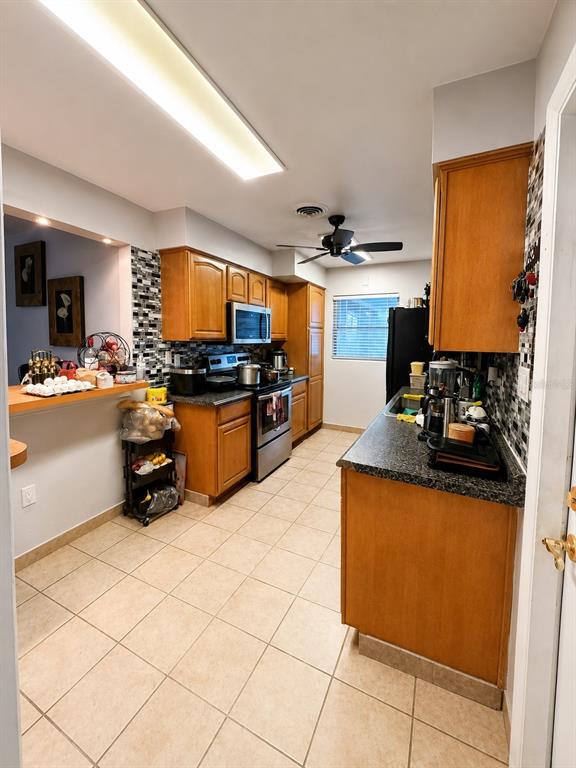 A kitchen with wood cabinets, dark countertops, tile flooring, and a ceiling fan — 811 HILLSIDE AVENUE, LAKE WALES, FL