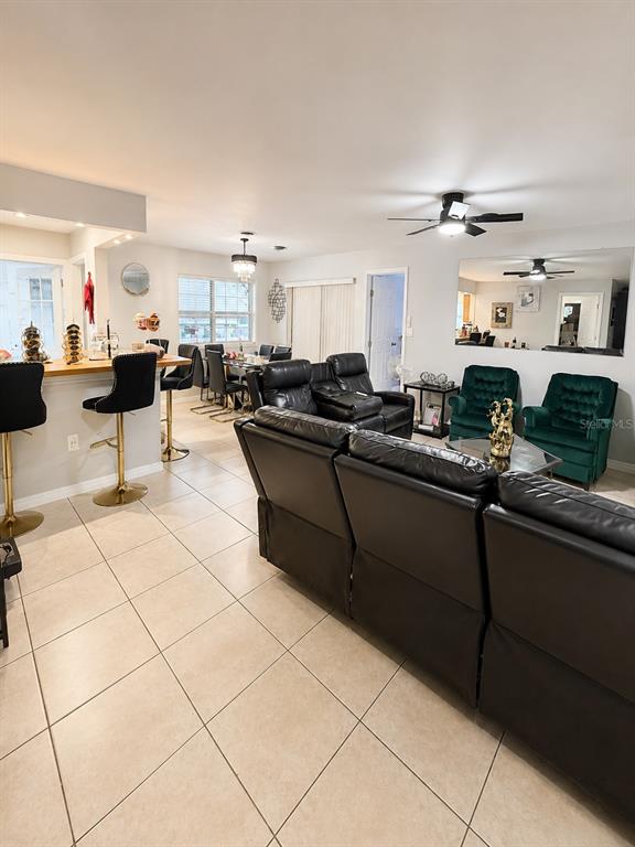 An open-concept living and dining area features tile flooring, black leather seating, and green armchairs — 811 HILLSIDE AVENUE, LAKE WALES, FL