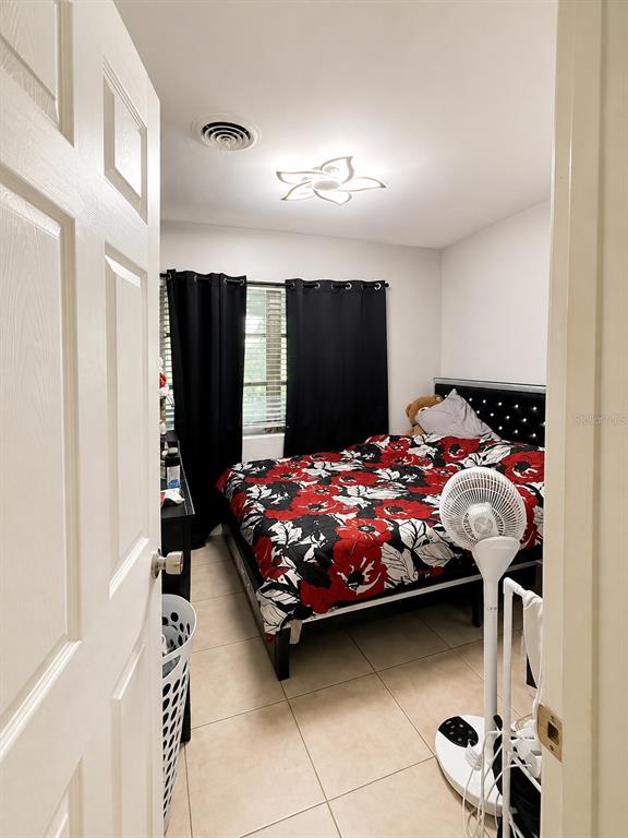 A bedroom features a bed with a floral comforter, black curtains, and a ceiling fan — 811 HILLSIDE AVENUE, LAKE WALES, FL