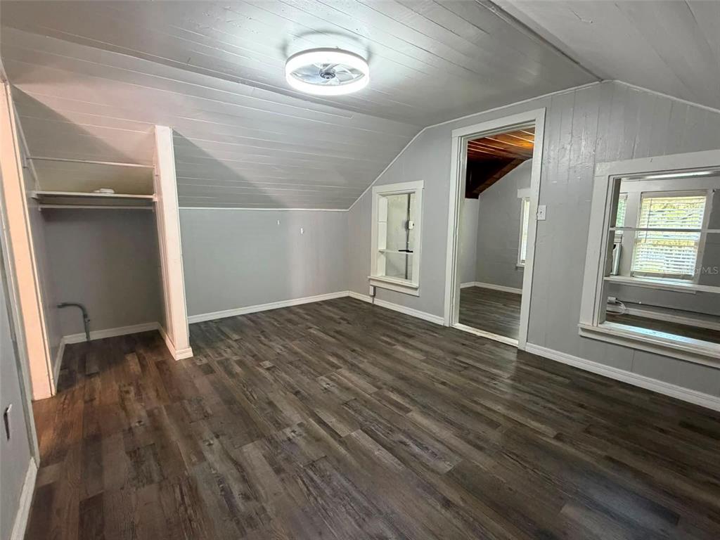 An attic bedroom with gray walls, wood-look flooring, a sloped ceiling, and a ceiling fan — 41014 FLETCHER ROAD, UMATILLA, FL