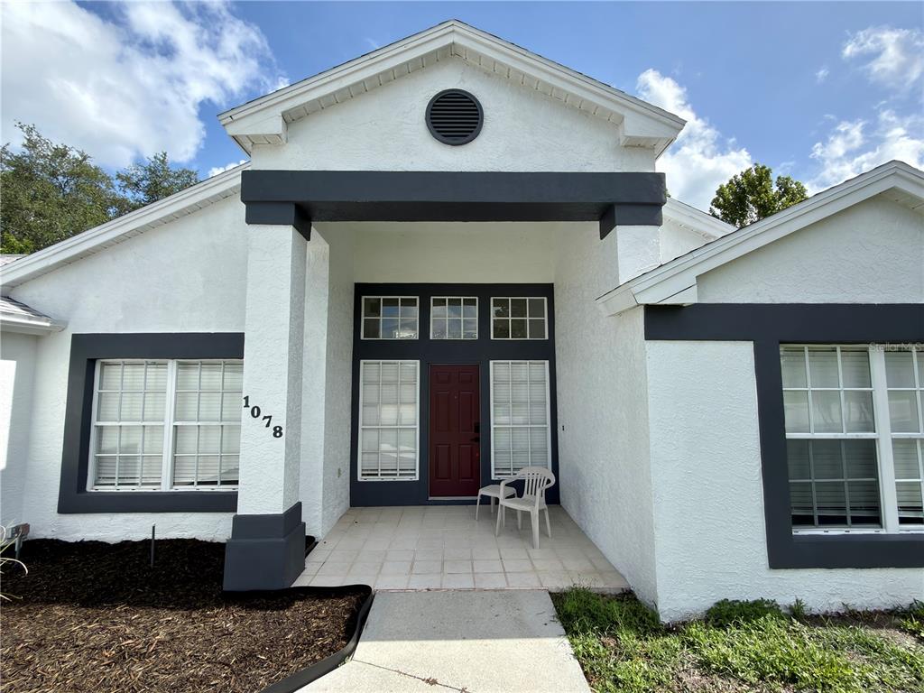 The exterior of a white house features a dark-trimmed entryway and a red front door — 1078 S SOFTWIND LOOP, LECANTO, FL