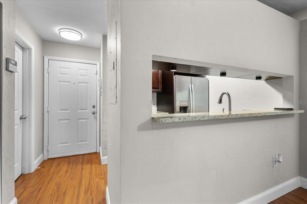 A view of an entryway with wood flooring and a kitchen pass-through window — 4000 SW 23RD STREET UNIT 4-105, GAINESVILLE, FL