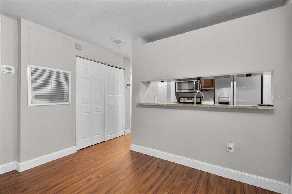 A room with wood-look flooring features a pass-through window looking into a kitchen — 4000 SW 23RD STREET UNIT 4-105, GAINESVILLE, FL
