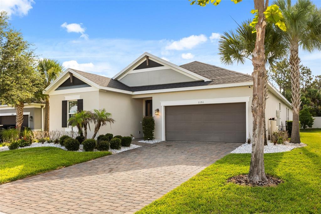 A single-story house with a paved driveway, two-car garage, and palm trees in the yard — 1151 LAKESIDE ESTATES DRIVE, APOPKA, FL