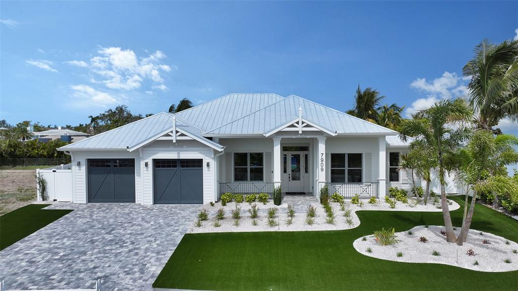 A white single-story house with a metal roof, two-car garage, and landscaped front yard — 8009 20TH PLACE W, BRADENTON, FL
