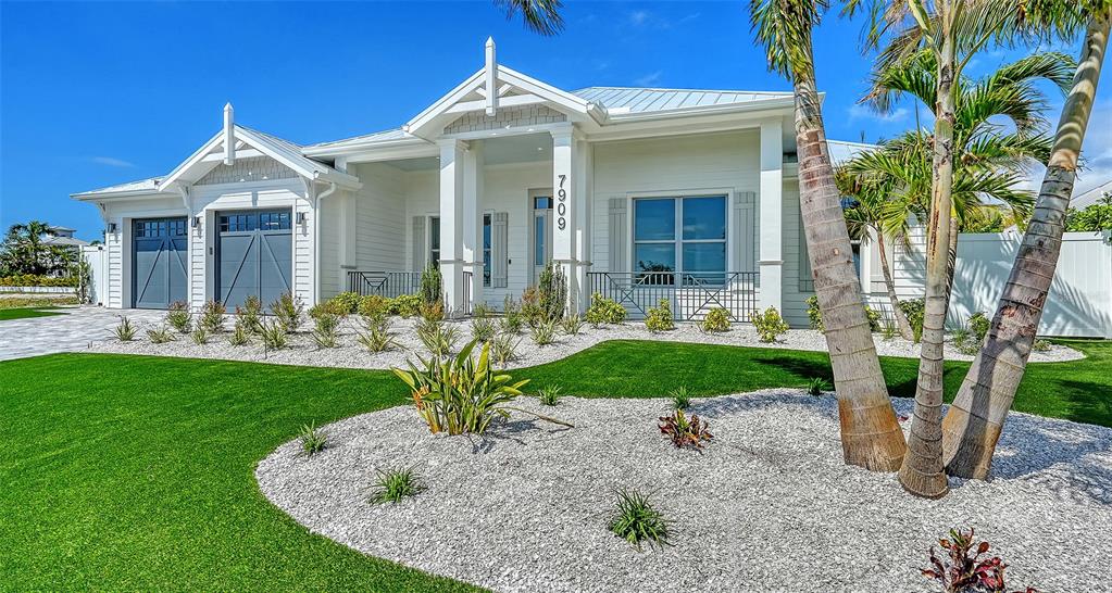 A white single-story house with a metal roof, gray garage doors, and landscaped front yard — 8009 20TH PLACE W, BRADENTON, FL