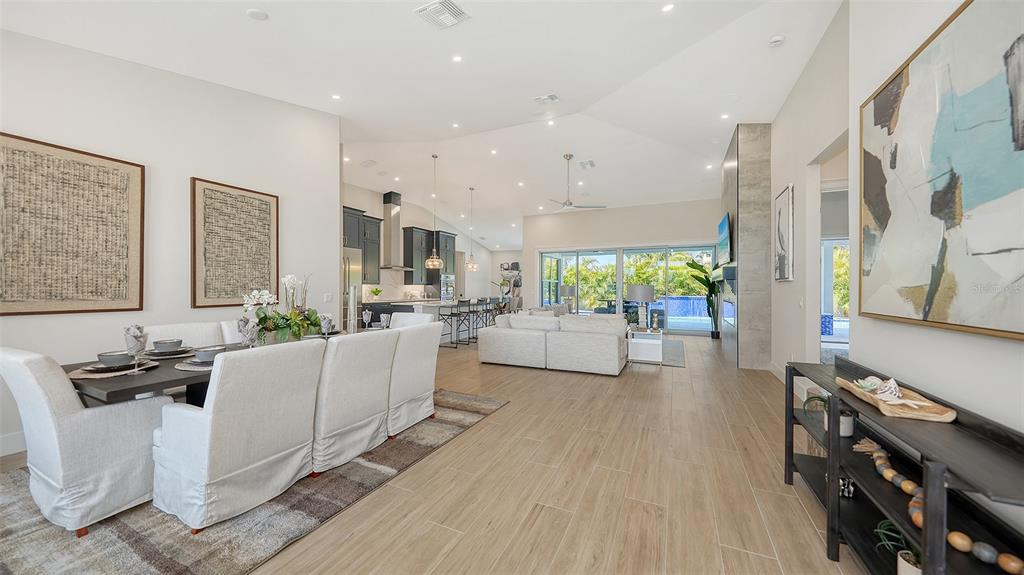 An open-concept living and dining area features light wood-look tile floors and a vaulted ceiling — 8009 20TH PLACE W, BRADENTON, FL